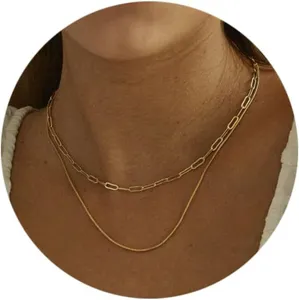Close-up view of a double-layered gold necklace featuring paperclip and snake chains.