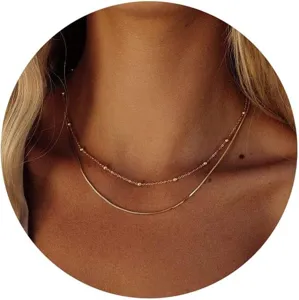 Macro detail of trendy gold layered necklace set with satellite and snake chain strands.