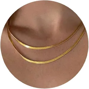 Close-up detail of layered gold-tone thin herringbone snake chain necklaces