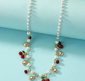 Dettaglio della collana con ciondolo a ciliegia e cuore con eleganti perle finte bianche