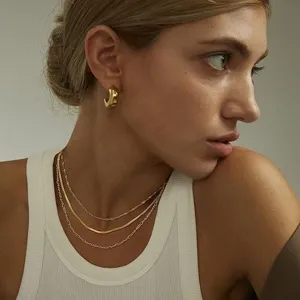 Elegant gold layered chain necklace set with snake and Figaro links worn by a model