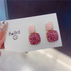 Close-up of elegant pink enamel square earrings with sparkling rhinestone clusters
