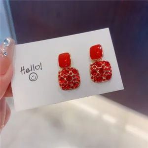 Close-up of red enamel and rhinestone pave square earrings on a white display card
