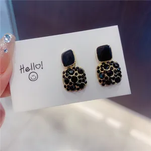 Detailed macro shot of vintage black enamel square earrings with sparkling crystal studs