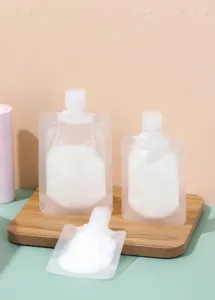 Set of three matte translucent travel squeeze pouches for lotion on a wooden base.