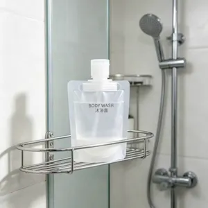 Clear portable travel dispensing pouch for body wash placed on a bathroom shower rack