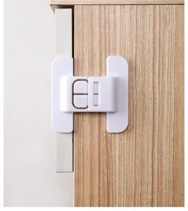 Close-up of a white baby safety lock securely installed on a wooden cabinet door