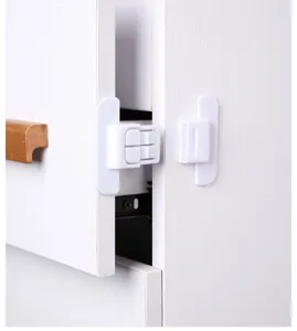 Close-up of a white plastic child safety lock installed on a wooden cabinet drawer.
