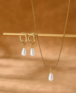 Detailed macro shot of elegant gold jewelry set featuring white teardrop pearl pendants