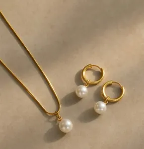 Detailed view of an elegant gold snake chain pearl necklace and hoop earrings set