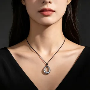 Macro detail of minimalist silver-tone organic geometric pendant on thin black cord necklace
