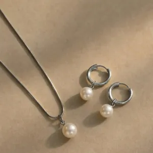 Elegant pearl jewelry set with minimalist necklace and hoop earrings on warm background