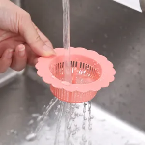 Roze bloemvormige gootsteenzeef filtert stromend water in een stalen gootsteenbak