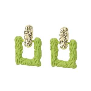 Detailed macro shot of Korean style green textured square earrings with gold accents