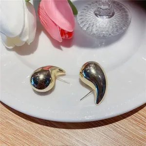Gros plan de boucles d'oreilles dorées en forme de goutte d'eau sur une assiette.