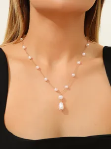 Elegant gold chain necklace with white pearls and a teardrop pendant worn by a model