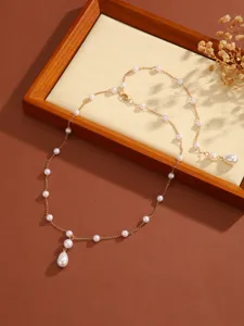 Close-up of a refined gold pearl necklace with a teardrop pearl pendant