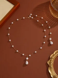 Elegant gold-tone chain necklace with scattered pearls and teardrop pendant detail