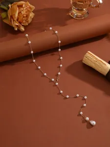 Close-up of an elegant Y-shaped gold chain necklace with pearls and a teardrop pendant.