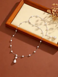 Macro detail of an elegant pearl fringe necklace with a teardrop pendant on a wooden display