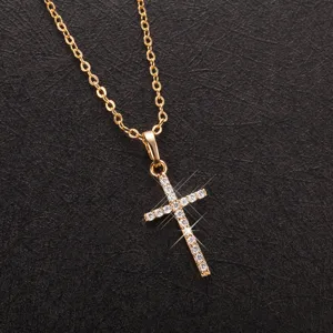 Close-up of a sparkling gold-toned cross pendant necklace with clear zircon stones.