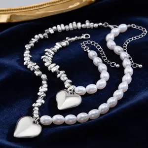 Macro detail of glossy metal heart pendant and white irregular pearl necklace set