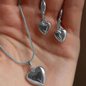 Elegant silver heart-shaped necklace and earrings jewelry set displayed in human hand