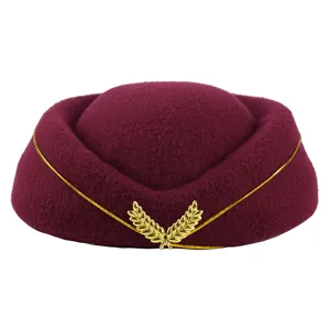 Vue détaillée d'un chapeau de stewardess bordeaux avec décoration d'emblème de feuille dorée