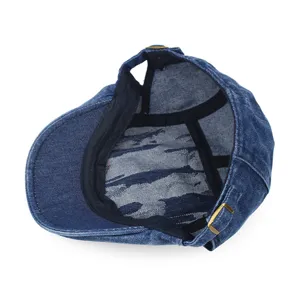 Detailed interior view of a retro blue denim flat cap showing the lining and metal buckle.
