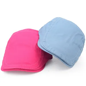Close-up detail of hot pink and light blue cotton beret caps with visible stitching on brims