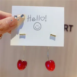Detailed close-up of long burgundy cherry drop earrings hanging from a white display card