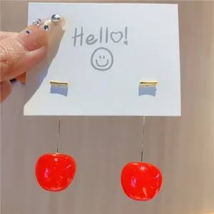 Detailed close-up of wine red long cherry drop earrings on a white card.