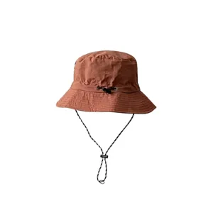 Detail showing the adjustable chin strap and fabric texture of the terracotta bucket hat.