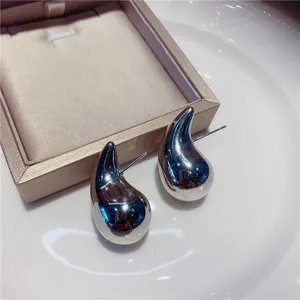 Vue détaillée de boucles d'oreilles gouttes métalliques argentées au fini miroir