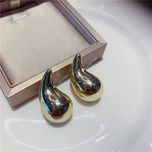 Gros plan d'élégantes boucles d'oreilles clous en métal doré en forme de goutte
