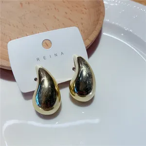 Gros plan détaillé de boucles d'oreilles clous dorées en forme de goutte d'eau sur carte