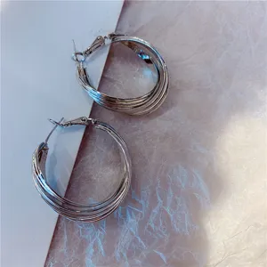 Close-up detail of silver-colored multi-layer hoop earrings with textured background.