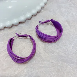 Detail of purple multi-layer hoop earrings with matte finish on textured background.