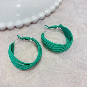 Close-up of large green multi-layer exaggerated metal hoop earrings with elegant texture
