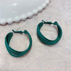 Close-up detail of dark green multi-layered hoop earrings with a chic matte finish