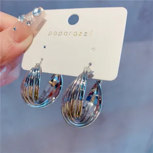 Detailed macro view of stylish multi-layer silver hoop earrings on white card display
