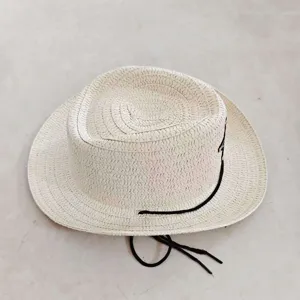 Chapeau de paille crème pour enfants avec cordon noir et détail étoile, vue de près.