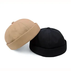 Detailansicht von khakifarbenen und schwarzen Baumwoll-Skull-Caps ohne Krempe im Studio.