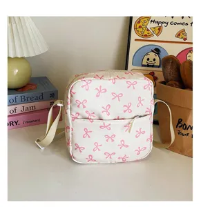 Detailed view of cute white square crossbody bag with pink bow patterns and front pocket