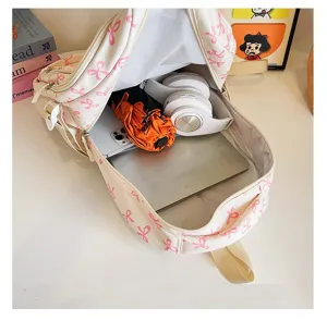 Close-up interior detail of large capacity cream backpack with pink bow pattern for laptops