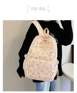 Detail of creamy white backpack featuring pink bow patterns and a 'Hello weekend' patch