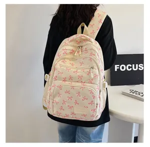 Back view of a student wearing a cream backpack with pink ribbon patterns.