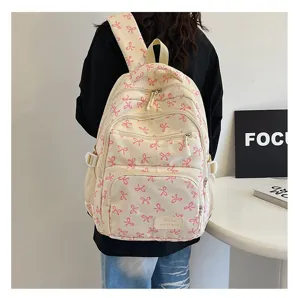 Back view of a model wearing a cream canvas backpack featuring pink bow patterns