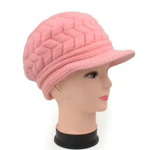 Seitenansicht einer rosa gestrickten Wintermütze mit dickem Zopfmuster auf einem Modell.