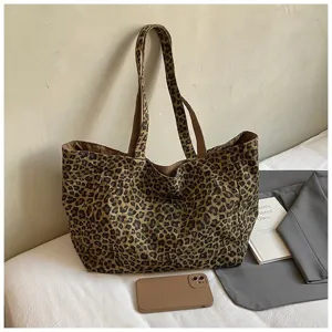 Large capacity leopard print canvas tote bag placed with everyday items in lifestyle setting